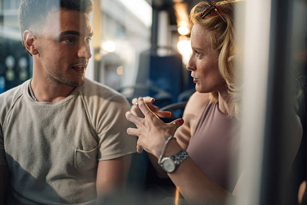 Young woman gesturing while talking to a man on the bus