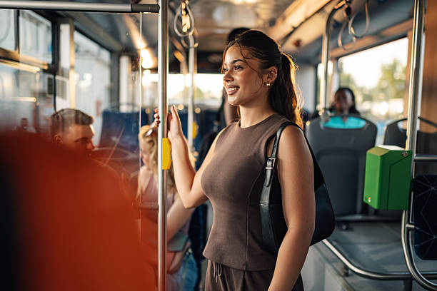 istock Young woman standing on a moving bus holding onto a pole 2224225772