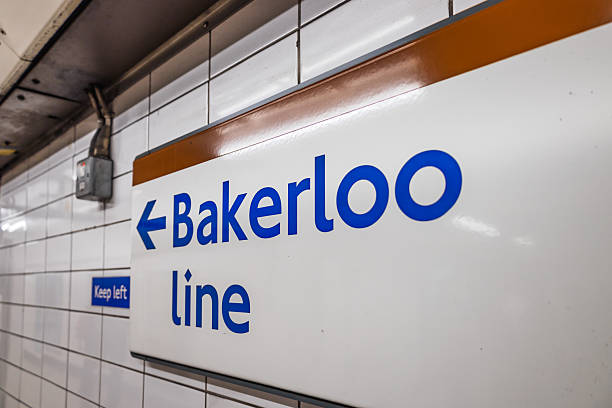 Close up Bakerloo Line sign with blue text and arrow on white tiles inside London Underground, guiding commuters to the platform. London, UK, 5 May 2024