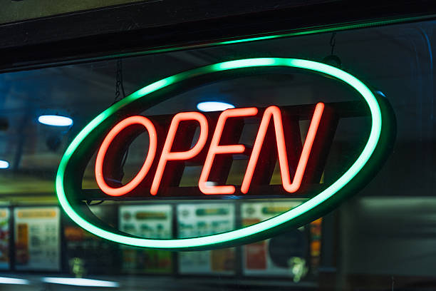istock Bright Neon OPEN Sign with Green Oval Border Illuminated at Night on Storefront 2224226874