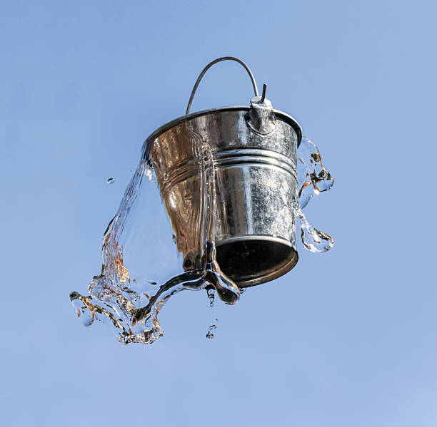 istock A falling bucket splashes water, on a background of blue sky. 2224227845