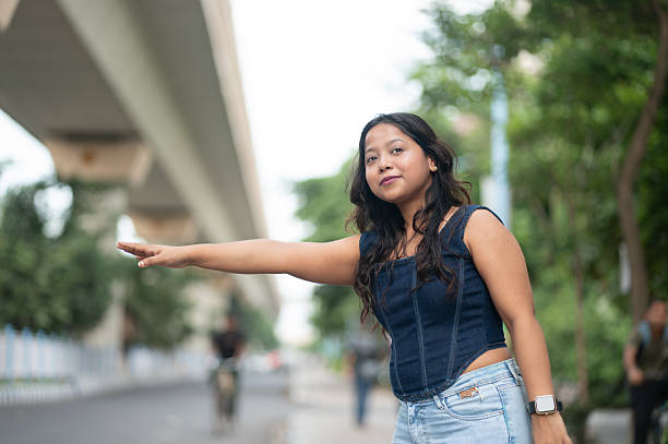 Confident female posing with arm extended beside an urban road, showing casual style and confident body language.