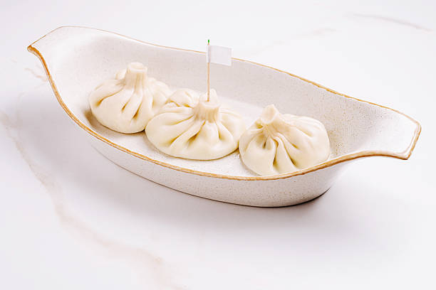 istock Three traditional Georgian khinkali dumplings arranged in a cream-colored ceramic dish 2224235583