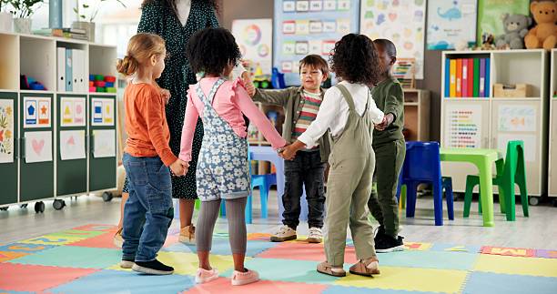 istock Group, children and holding hands with teacher in circle for playing, game and fun activity at recess. Montessori, kids and learning break for classroom community, motor skills and growth development 2224235772