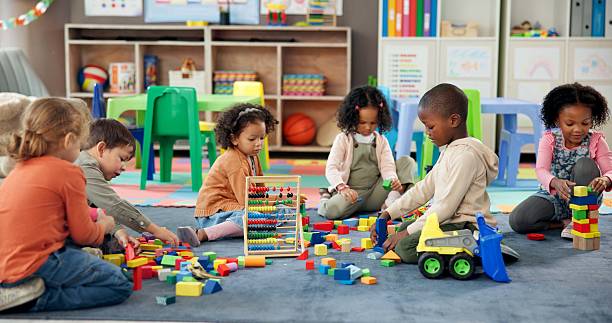 kids, students and play with blocks in classroom for learning, problem solving and creative activity. children, toys and floor for education game, puzzle solution and motor growth in kindergarden - oynak stok fotoğraflar ve resimler