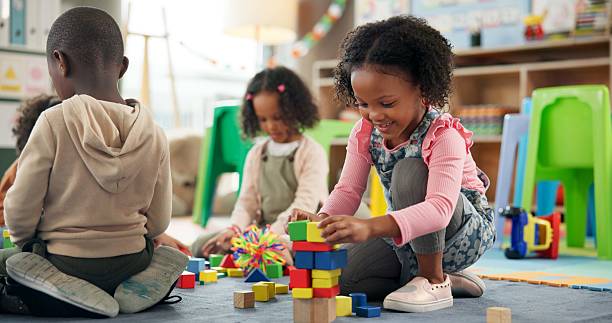 istock Education, child and playing with building blocks in classroom for creative activity, development or learning. Happy, girl student or stack toys at kindergarten for gross motor skills or coordination 2224235789