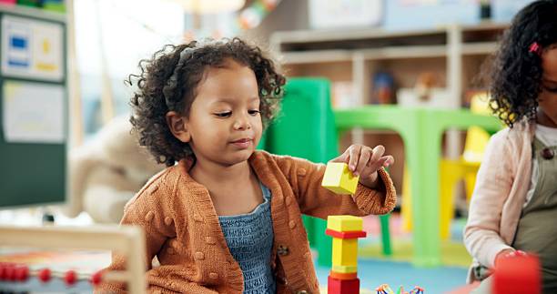 istock Education, girl and playing with building blocks in classroom for creative activity, motor development and learning. Child student, kindergarten and stack toys for problem solving and coordination 2224235790