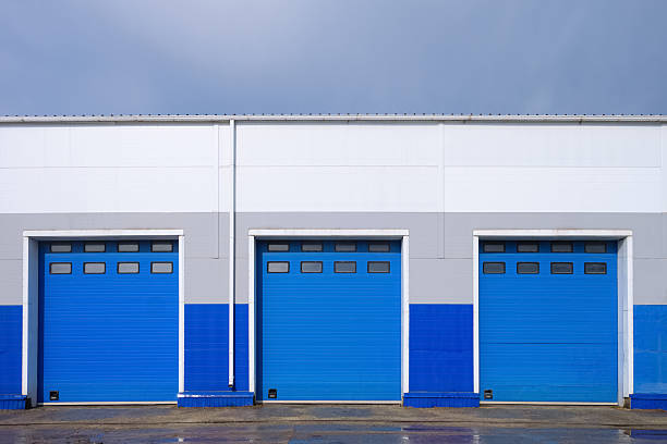 istock Row of overhead sectional gates in a multi-seat cargo truck garage. Outdoors front view. 2224238430