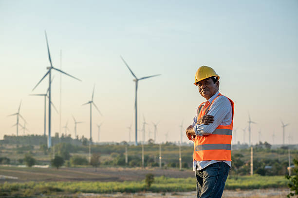 istock Senior engineer smiling while standing in wind farm. Renewable energy industry, portrait 2224240235