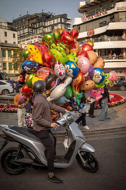 A Vietnamese man on a scotter stops to buy a helium filled balloon shaped as an animal in Dong Kinh Nghia Thuc Square, Hanoi, Vietnam
