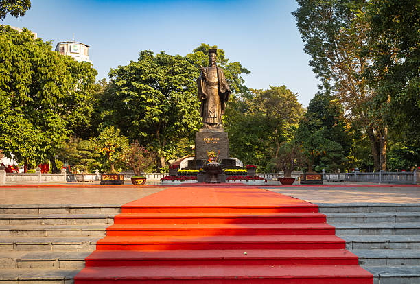 The iconic statue of revered Vietnamese king Le Thai To who lived from 974 - 1028  next to Hoan Kiem Lake in central Hanoi, Vietnam.\nThe park around the statue is a popular place for families to visit and children to play in the cool of the evening.