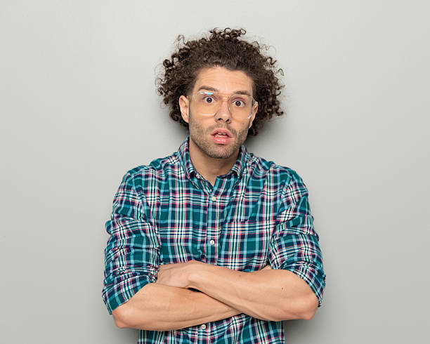 istock surprised young man with glasses crossing arms and making a silly face 2224250744