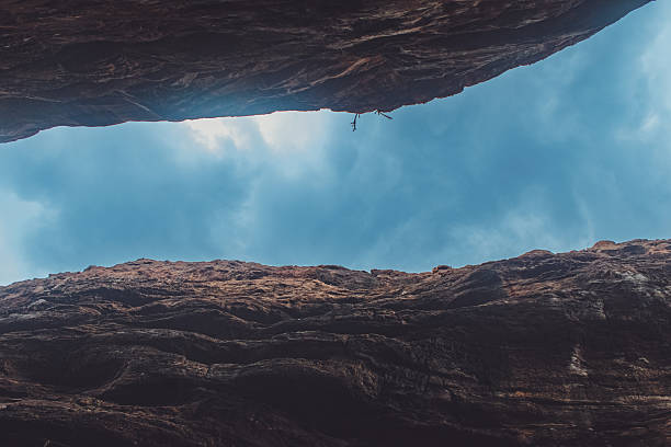 Skyward view of a narrow canyon between red sandstone cliffs in Badami, Karnataka, India.