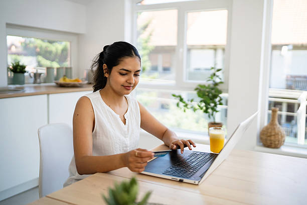 istock Young Indian woman completes an online transaction from home, using her laptop and credit card securely. 2224251876