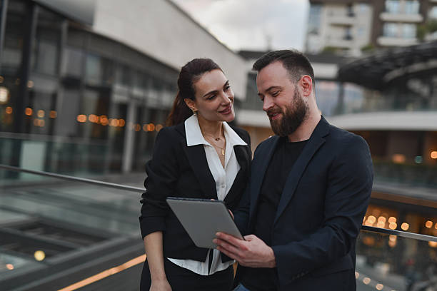 istock Attractive Colleagues Reviewing Event Photos On Tablet While Smiling During Casual Break On Balcony 2224252206