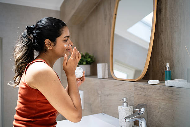 istock Young Indian woman applying a face cream in front of the mirror 2224252500