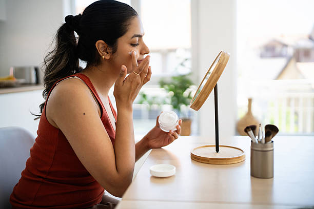 Young Indian woman applying a face cream in front of the mirror