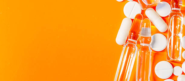 istock A composition of various medical preparations — white tablets, capsules, and clear ampoules — is elegantly arranged on a rich orange background. 2224255434
