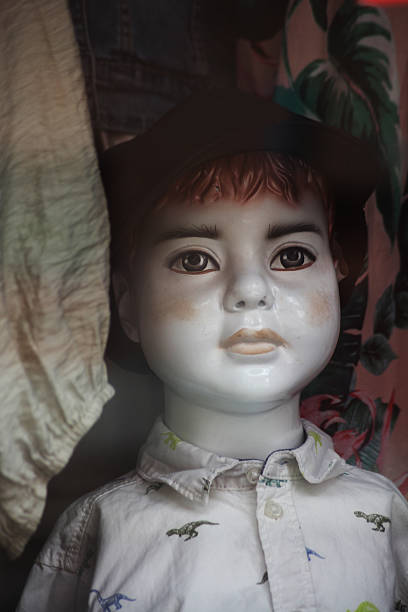 Child mannequin stands in modern store setting, showcasing minimalist design. Soft lighting highlights its detailed features, creating an elegant fashion display ambiance.