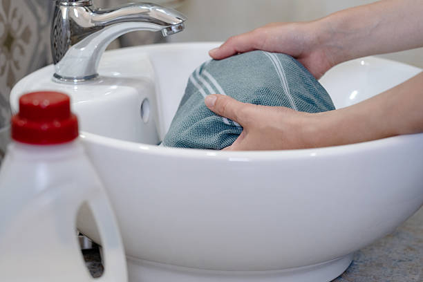 istock Hands washing cloth in an elegant white sink while water runs from a faucet in a bright laundry room 2224257363