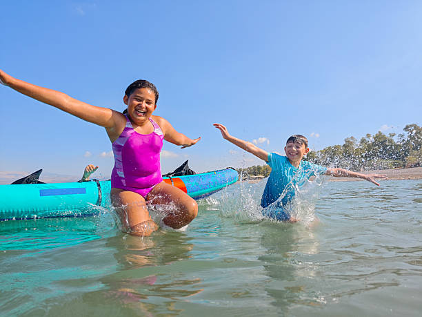 istock Joyful Splash: Kids Jumping from Kayak on a Bright Summer Day. 2224260698