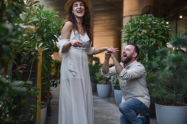istock Smiling Man Proposing To Beautiful Girlfriend In White Dress While She's Laughing Joyfully 2224260751