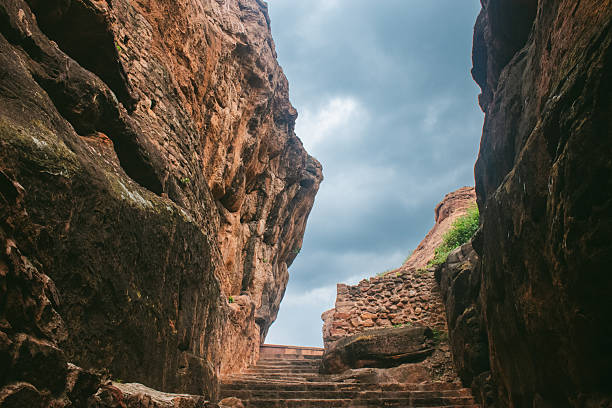 istock Ancient stone steps carved into reddish rock, leading through a narrow rocky canyon passage. 2224260776