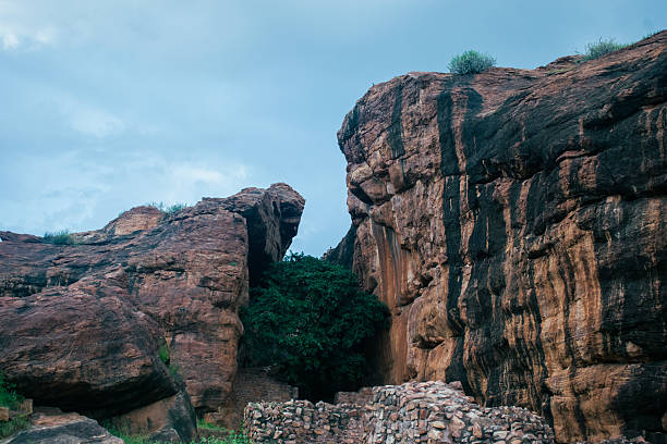 istock Towering reddish-brown cliffs split by a narrow crevice under a dramatic cloudy sky at Badami, karnataka, India. 2224260777