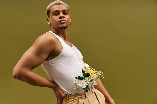 Young man showcases vibrant style with flowers in a creative studio setting