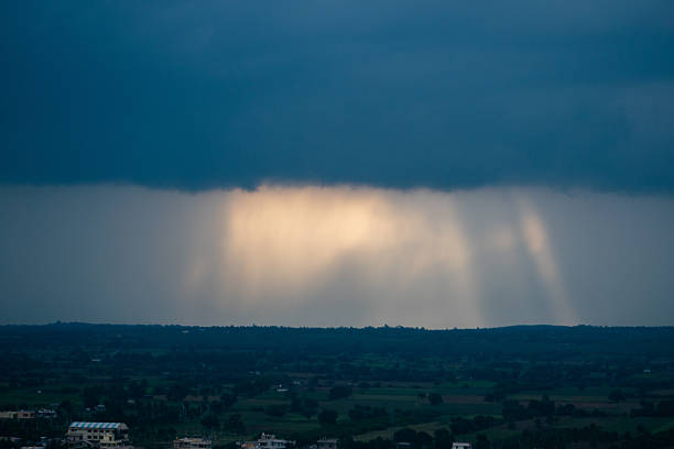 Heavy rainstorm pours down over the distant landscape under dark clouds.
