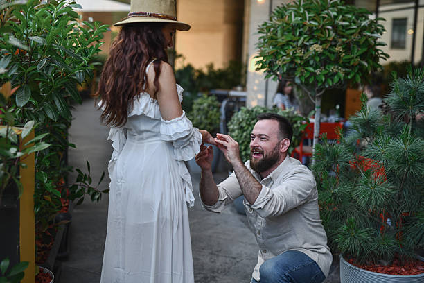 istock Loving Man Holding Ring While Girlfriend In White Dress is Smiling With Surprise 2224262000