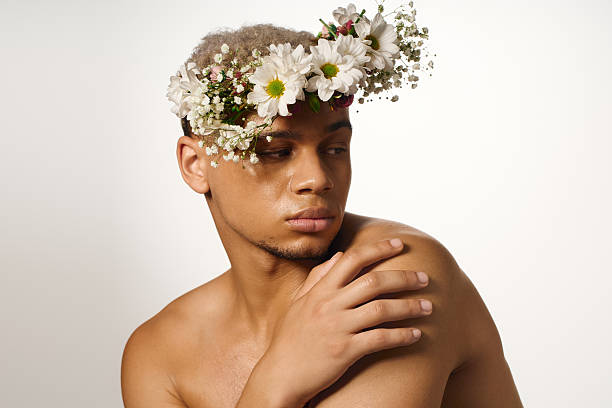 istock Muscular young man with dyed hair poses elegantly in a floral crown in studio setting 2224262255