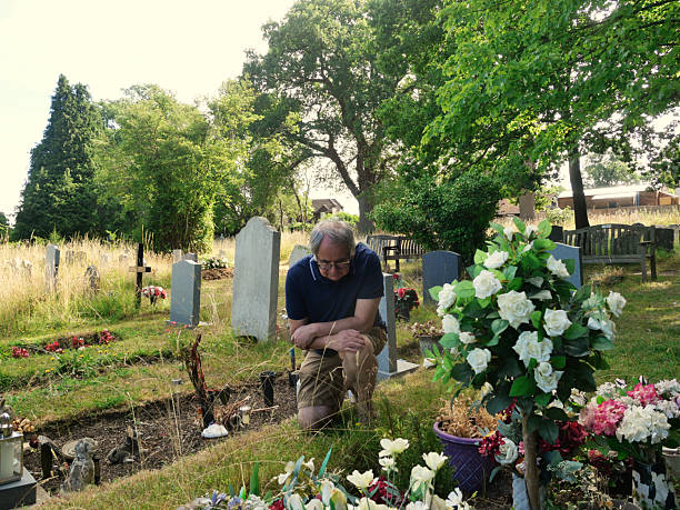 istock lderly Man kneeling at a graveside grieving and remembering a loved one a warm day 2224263280