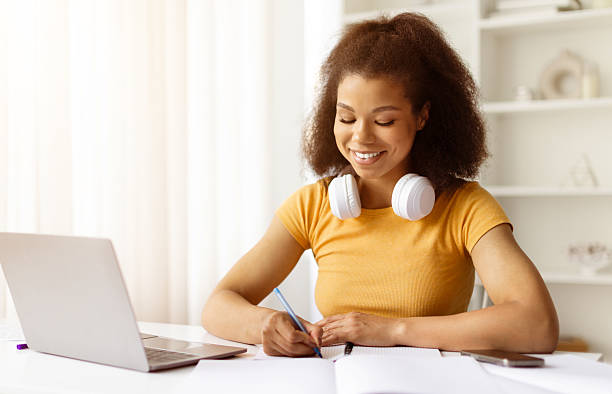 istock Young black woman writing in notebook during remote study at home 2224267402
