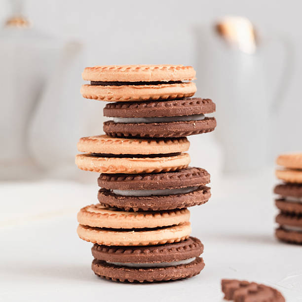 Stack of milk and chocolate cookies with cream filling. Bakery concept.
