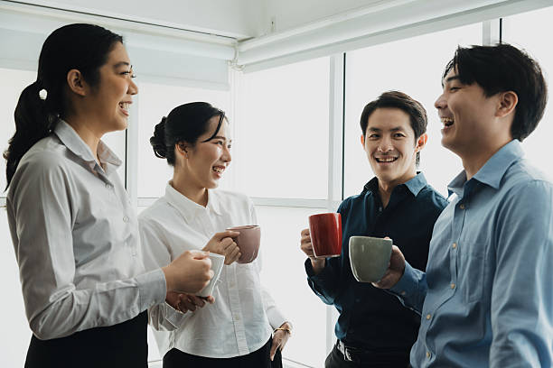 istock Group of colleagues sharing a light moment with coffee cups in modern office during daylight hours 2224271918