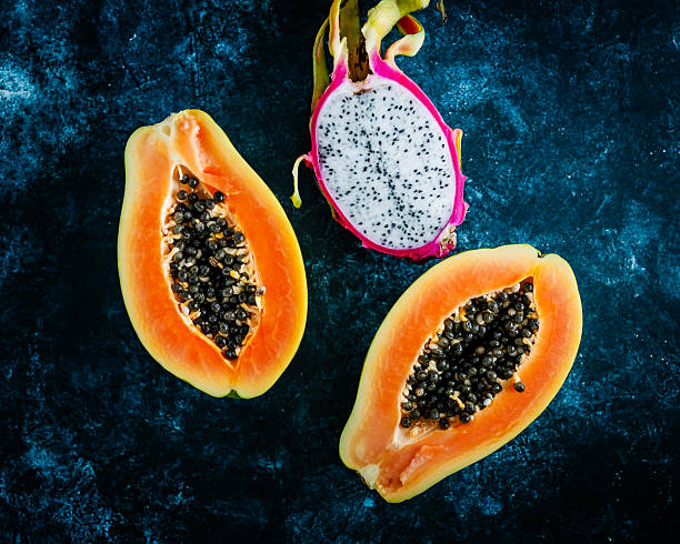 Pile of fresh, ripe papayas with green and yellow skin, perfect for healthy eating and tropical fruit themes. Shot in a market setting.
