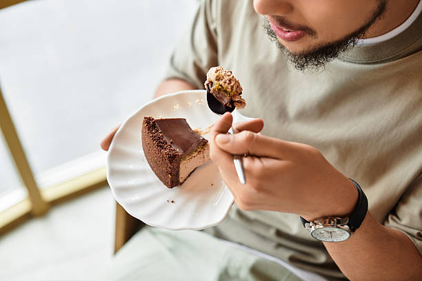 istock Young man enjoying cake in a vibrant cafe 2224273294