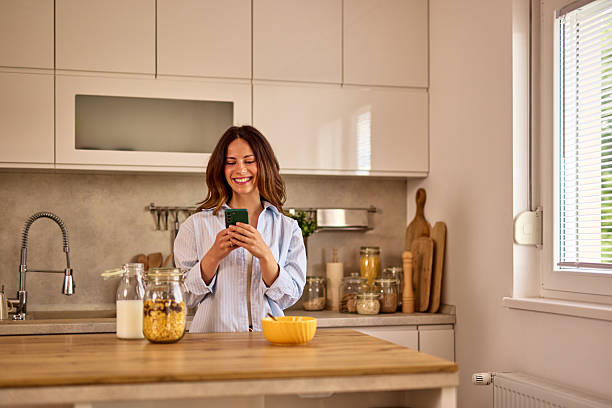 istock Young Woman Enjoying Breakfast and Using Smartphone in Modern Kitchen 2224274686