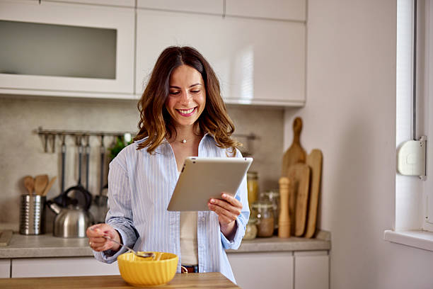 istock Smiling woman enjoying breakfast and using digital tablet in kitchen 2224274702