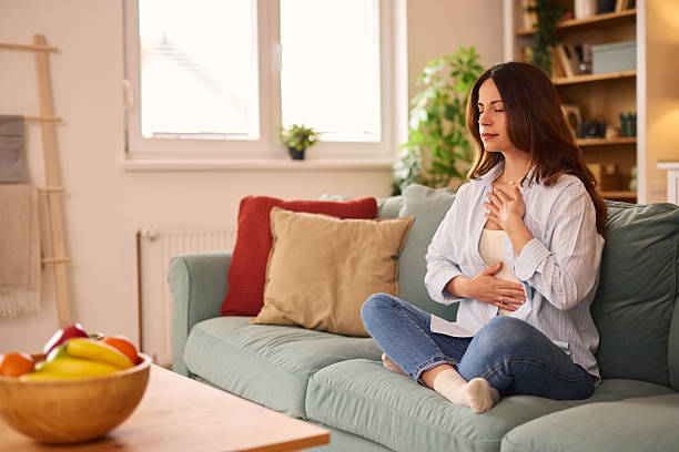 istock Serene woman practicing mindfulness breathing exercises on sofa at home 2224274868