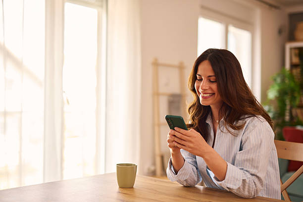 istock Young Woman Using Smartphone and Smiling at Home 2224274919