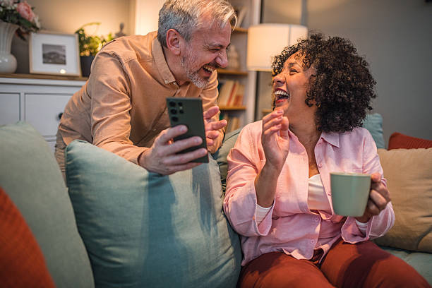 istock A carefree black woman sits on a sofa drinking tea while her husband shows her something on his mobile phone, which makes them have a lot of fun 2224278049