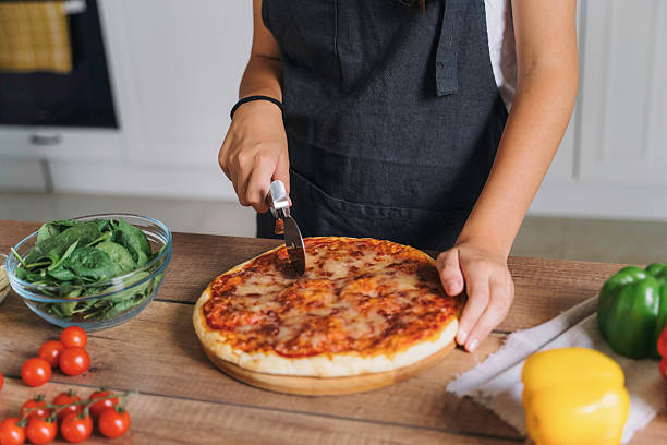 istock Delicious pizza being sliced in a home kitchen 2224284125