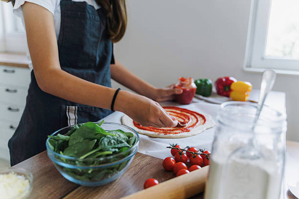 istock Creating Pizza with Tomato Sauce in Bright Kitchen 2224284150