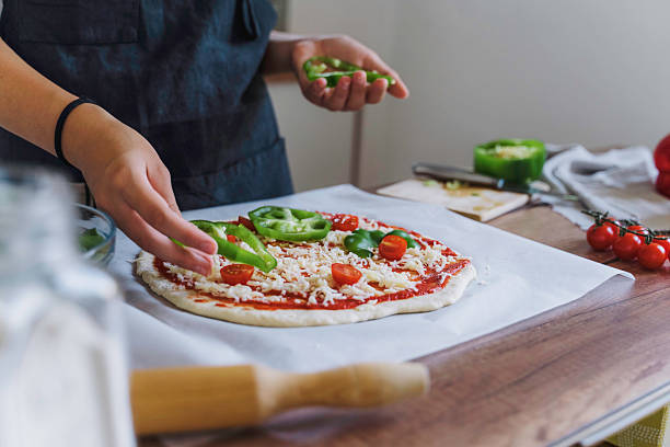 istock Placing Toppings on a Pizza in a Bright Kitchen 2224284158