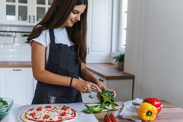 istock Girl Smiling While Preparing Pizza with Peppers 2224284219