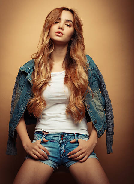 Young beautiful curly woman posing  over yellow background, studio shoot