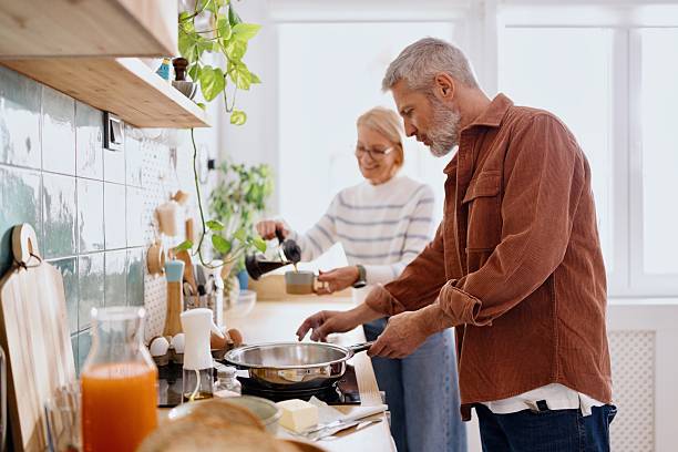 istock Mature Man Holding Pan While Wife Hands Him Ingredients 2224288877