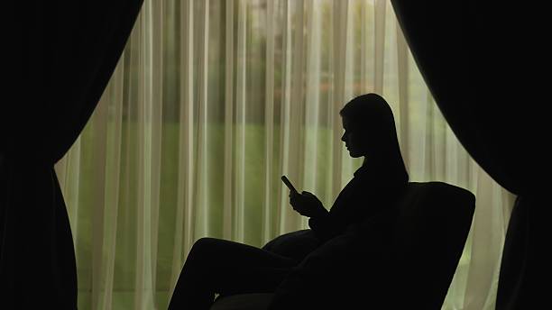 Silhouette of a Woman Using Smartphone by Window